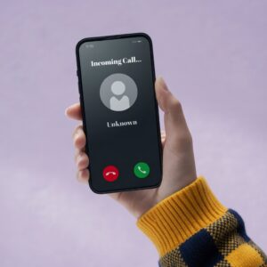 A hand holds a smartphone with an incoming call notification, displaying 'Unknown' and two call buttons.