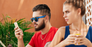Two people sit apart, each looking at a phone, illustrating how to know cheating.