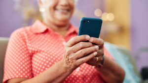 Smiling woman using a smartphone for reverse white pages lookup.