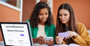 Two women checking a phone, illustrating how to find out who a phone number belongs to.
