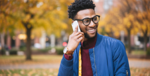 Smiling man using a smartphone outdoors for a cell phone directory.