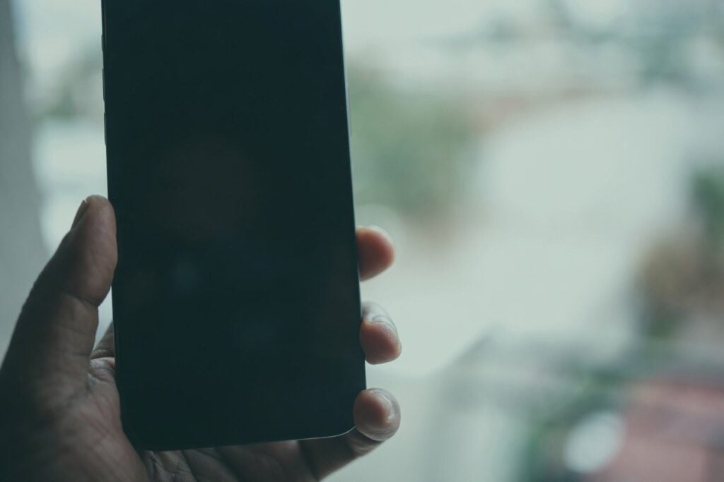 Hand holding a smartphone, suggesting secret dating profiles.