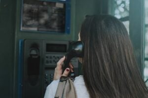 Woman using a payphone, illustrating report spectrum scam calls.