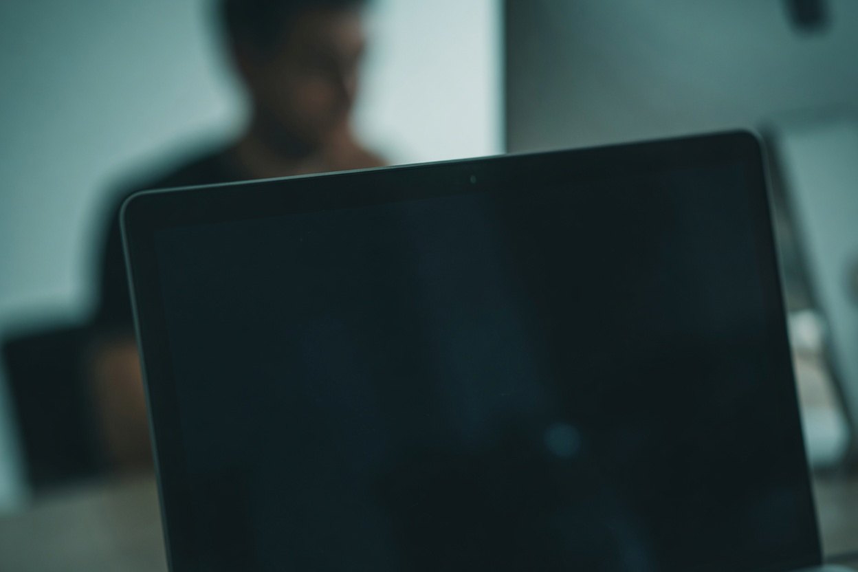 A laptop screen with a blurry background of a person.