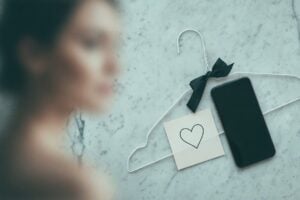 Blurred woman beside a phone and heart note on a hanger, for find someone on hinge free.