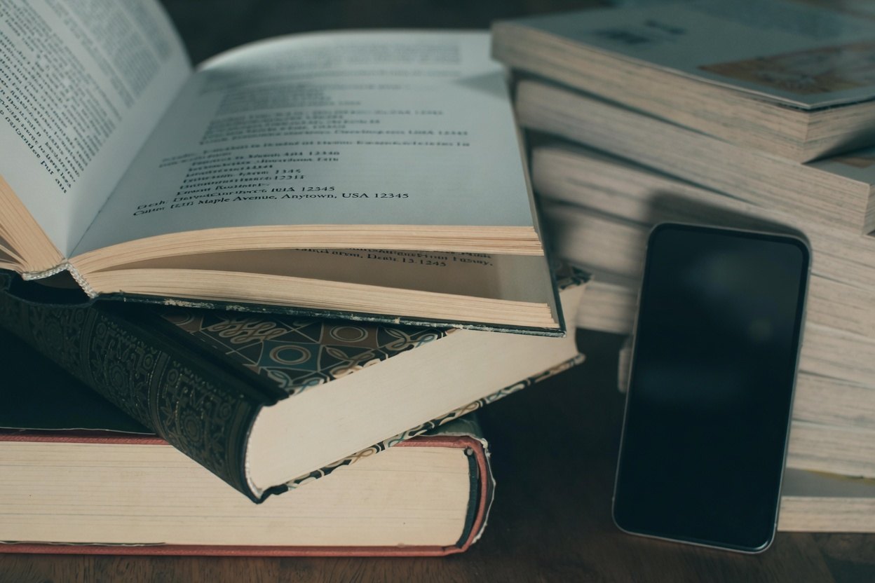 Current Address Lookup Guide 1 A stack of books with an open one and a smartphone next to it.