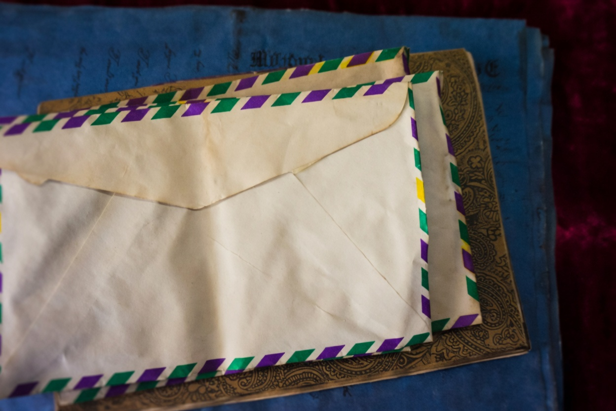 Signs of a Scammer 1 A white envelope with purple and green stripes on top of a blue book