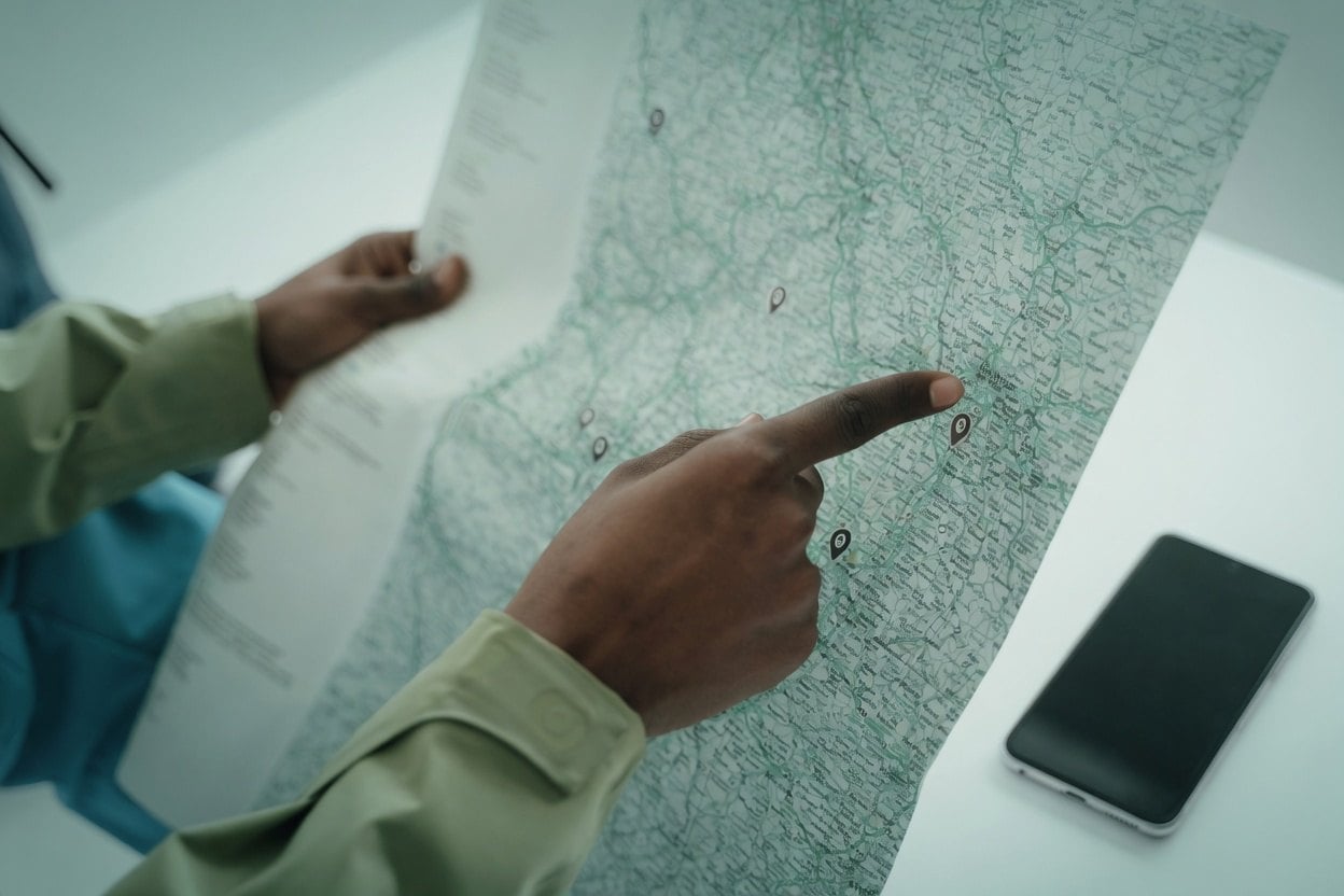 Airbnb Address Lookup Before Booking 2 A person pointing at a map with a smartphone nearby.