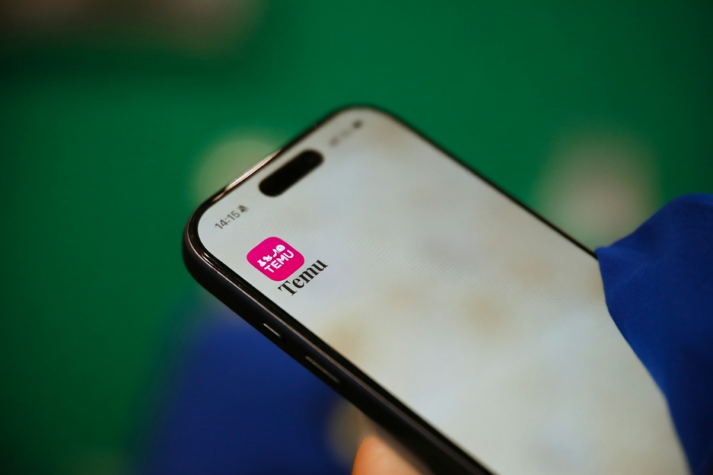 A hand holds a phone showing the Temu app, relevant to is temu safe.