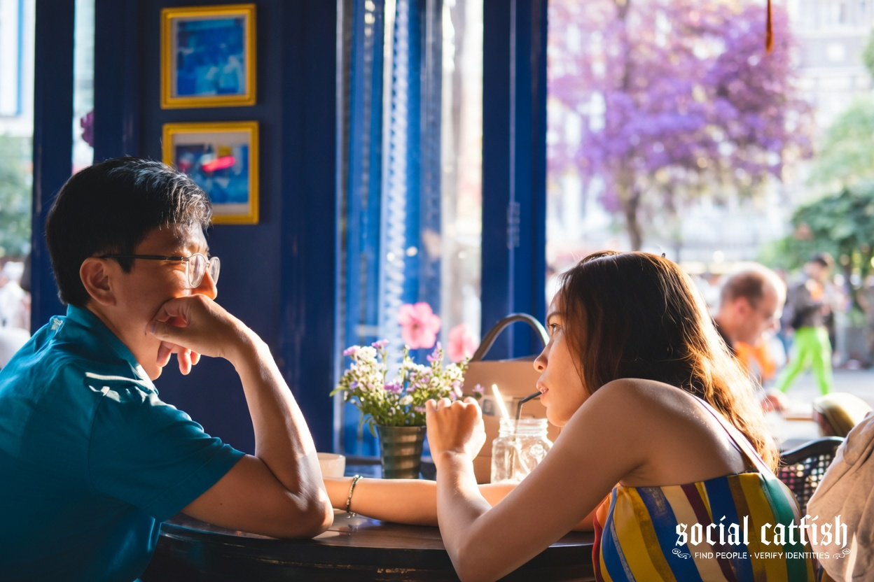 Is Hinge a Good Dating App? 2 A man and woman sitting at a table in a cafe, with a potted plant and flowers on the table