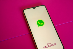 Phone on pink background showing an app icon, for how to find someone on whatsapp