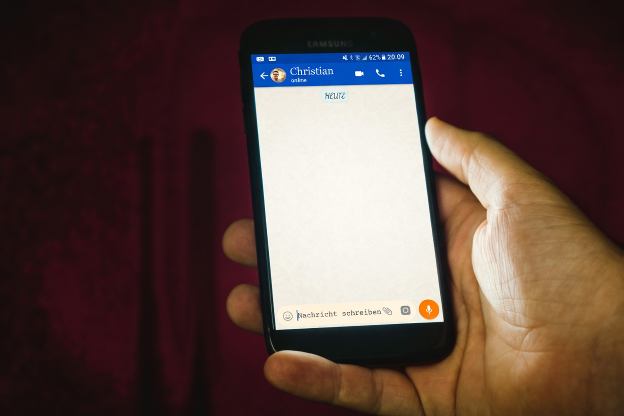 How to Find Someone on WhatsApp 1 A hand holding a smartphone with a white screen and a blue header displaying the name 'Christian'