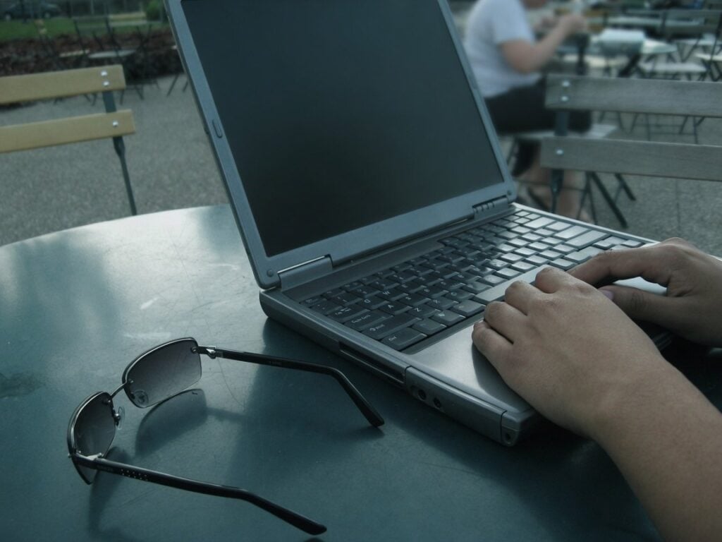 Person using a laptop beside sunglasses, illustrating best reverse email search.