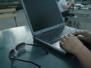 Person using a laptop beside sunglasses, illustrating best reverse email search.