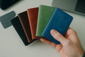 Hand holding colorful wallets and an RFID card, illustrating how does rfid blocking work.