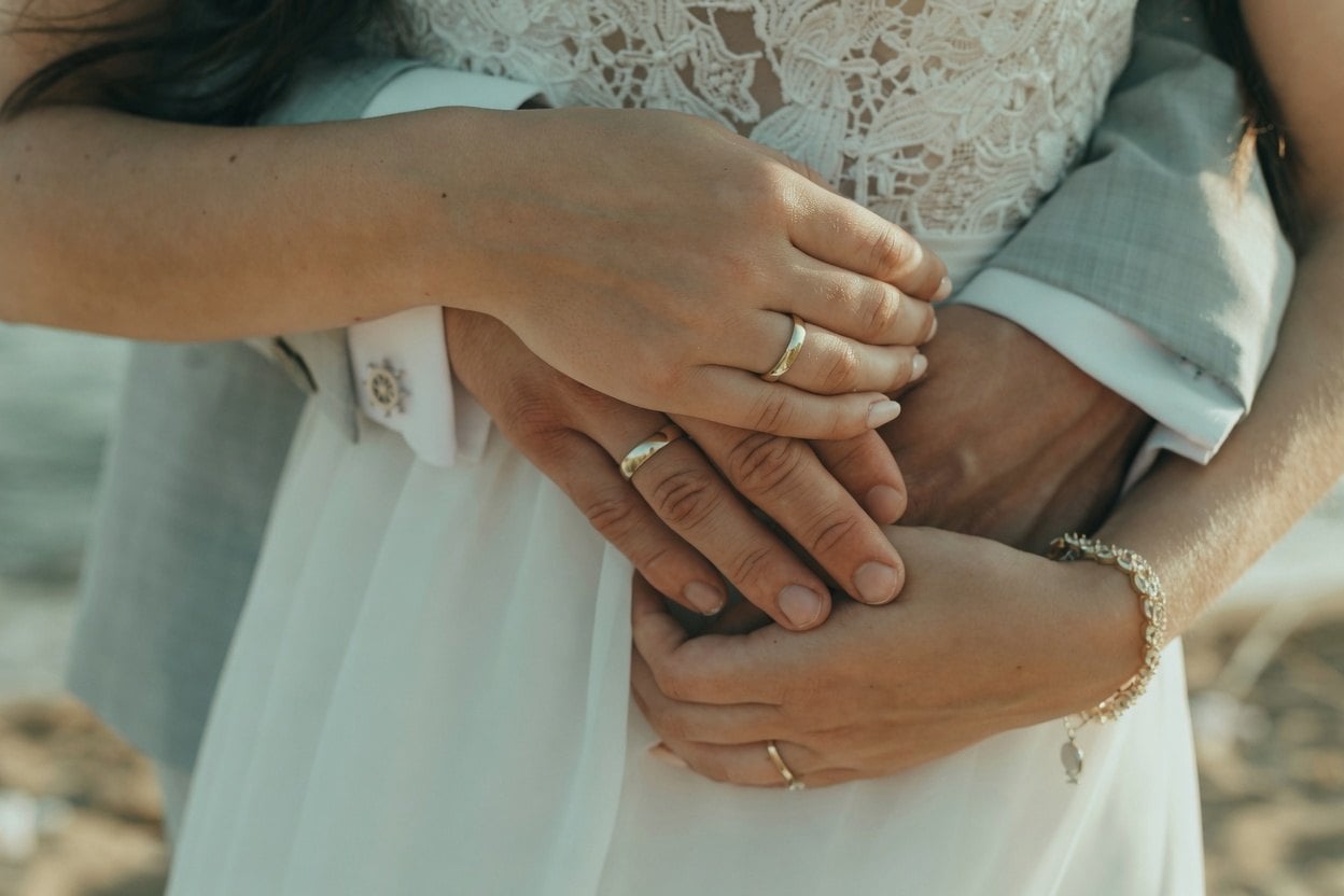 A bride and groom share a tender moment, their hands intertwined in a close embrace