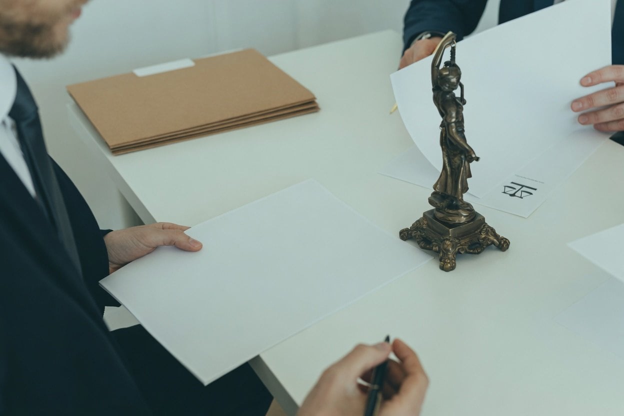 A man in a suit holding a piece of paper with a statue of a woman on a table