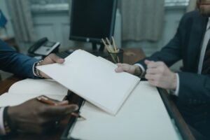 Two businesspeople review documents at a conference table, like a linkedin contact info email discussion.
