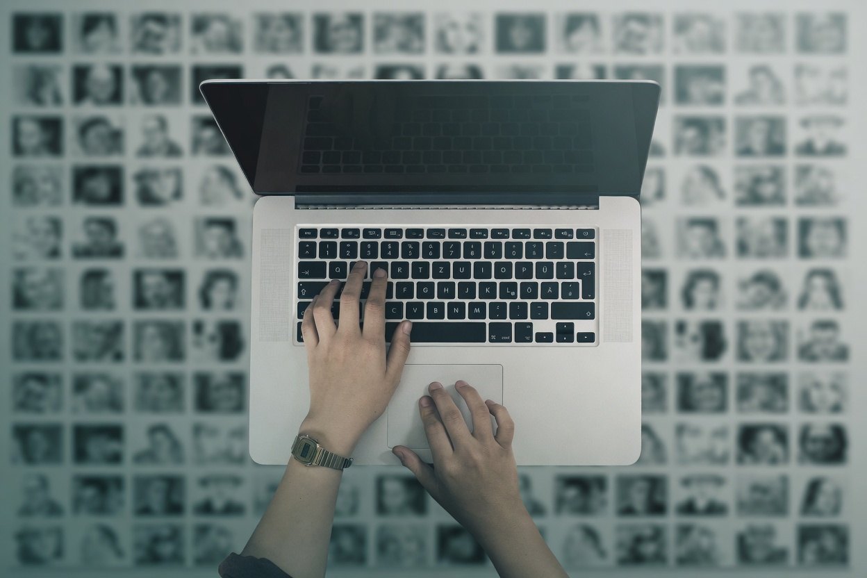 How to Find Contact Info on LinkedIn 1 A person typing on a laptop with a watch on their wrist, surrounded by a grid of small black and white