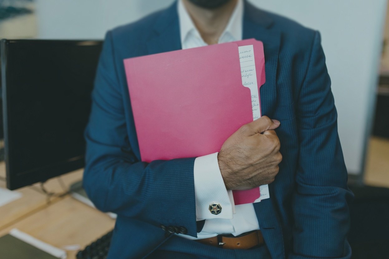 How to Find Contact Info on LinkedIn 2 A man in a suit holding a pink folder in his arms.