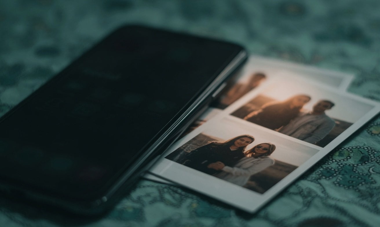 A smartphone with a Polaroid photo of two people on it