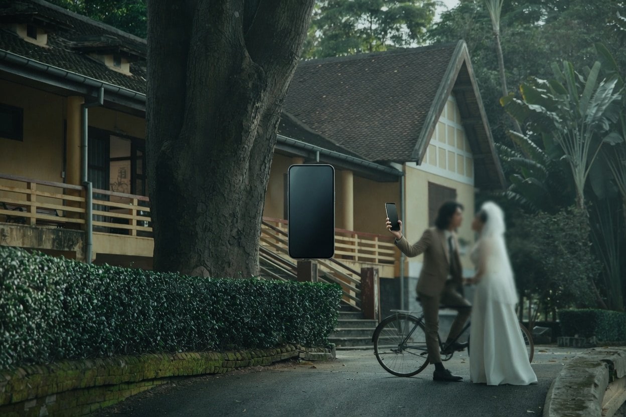 A couple on a bicycle with a wedding cake in the background.