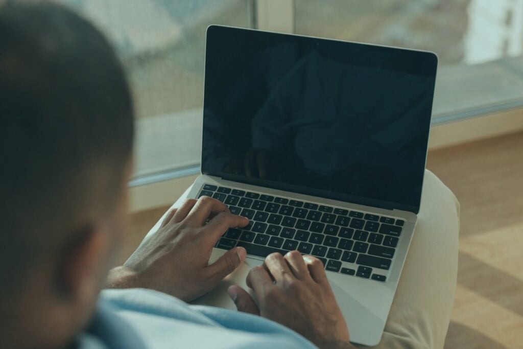 Person typing on a laptop, illustrating reverse icloud email lookup.