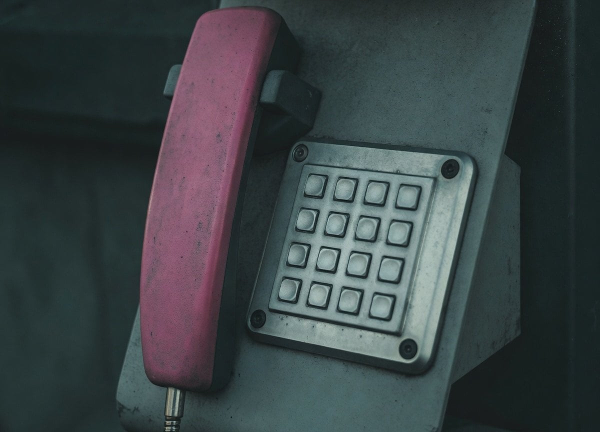 A red phone with a keypad on a metal surface