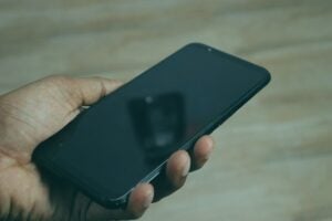 Hand holding a smartphone, social media reverse email search context.