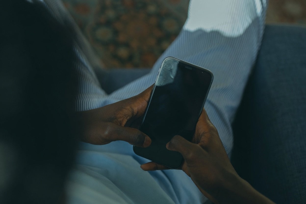 Social Media Reverse Email Search 1 A person holding a smartphone in their lap, with a blurred background.