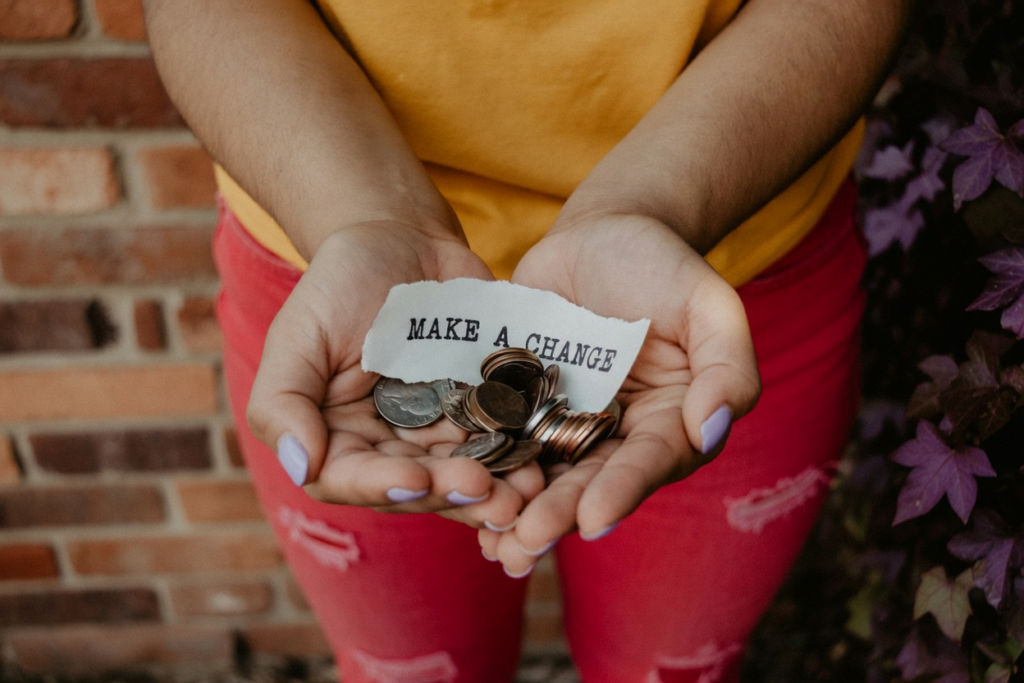 Hands holding coins and a paper note, suggesting a fake gofundme page.